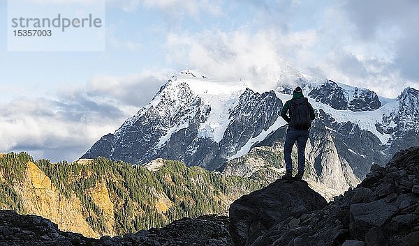 Beleuchteter Wanderer  der in die Ferne schaut  Tabletop Mountain  Blick auf den Gletscher Mt. Shuksan mit Schnee  Mt. Baker-Snoqualmie National Forest  Washington  USA  Nordamerika