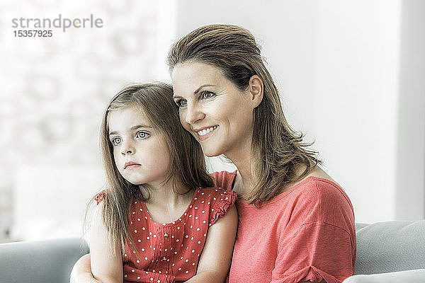 Mutter und Tochter sitzen zusammen auf der Couch und schauen in die Ferne  lächeln  Deutschland  Europa