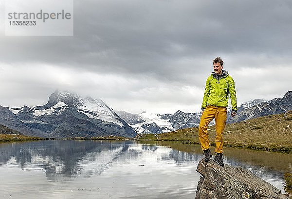 Wanderer steht auf Felsen  Stellisee  hinter Matterhorn  bewölkt  Wallis  Schweiz  Europa