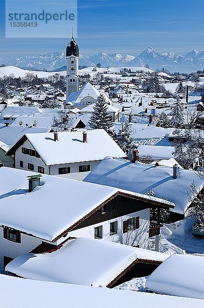 Blick auf schneebedeckte Dächer im Winter mit St. Andreas Kirche  Allgäuer Alpen im Hintergrund  Nesselwang  Allgäu  Bayern  Deutschland  Europa