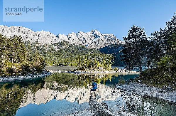 Wanderer auf Felsen stehend  Blick in die Ferne  Zugspitze und Wettersteingebirge mit Spiegelung im Eibsee  bei Grainau  Oberbayern  Bayern  Deutschland  Europa