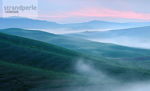 Morgenstimmung in der Toskana  hügelige Landschaft mit Nebel in der Morgendämmerung  hinter der Stadt Pienza  Val d'Orcia  Toskana  Italien  Europa