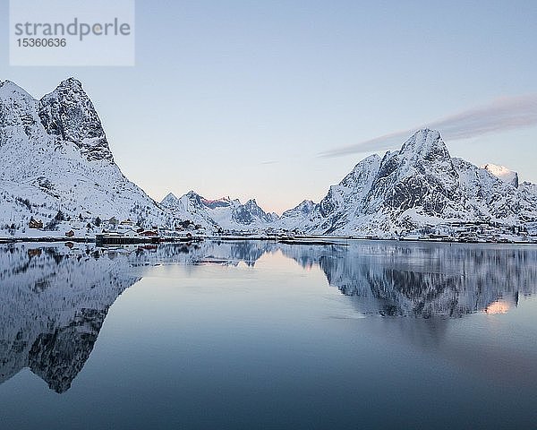 Verschneite Berge spiegeln sich im Fjord  Sonnenaufgang  Drohnenaufnahme  Reine  Lofoten  Norwegen  Europa