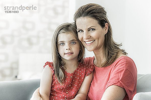 Mutter und Tochter sitzen zusammen auf der Couch und schauen in die Kamera  lächeln  Deutschland  Europa
