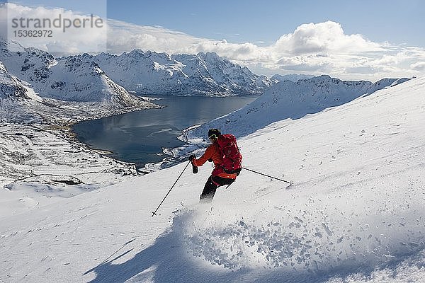 Skifahrer bei der Abfahrt vom Pilan mit Blick auf einen Fjord  Austvågøy  Lofoten  Norwegen  Europa