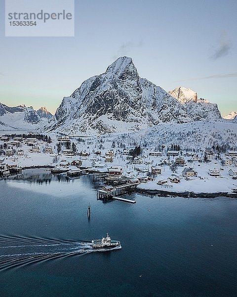 Ort Reine voe verschneiten Bergen mit Passagierboot  Drohnenaufnahme  Lofoten  Norwegen  Europa