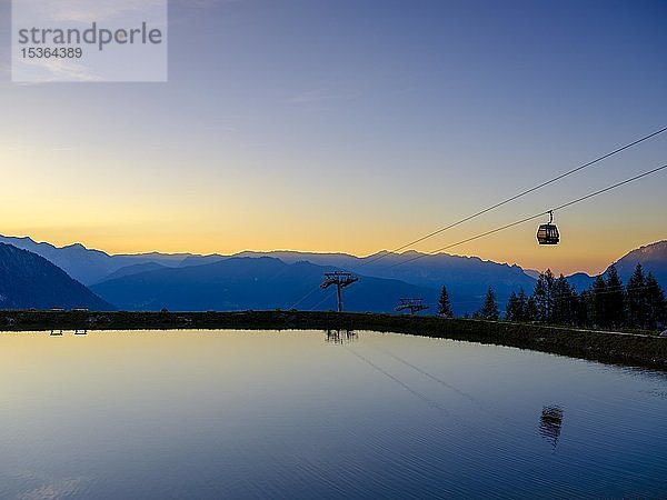 Alpenpanorama  Gondel der Jennerbahn spiegelt sich im Abendlicht in einem künstlichen Bergsee  Jenner  Berchtesgadener Alpen  Schönau am Königssee  Berchtesgadener Land  Oberbayern  Bayern  Deutschland  Europa