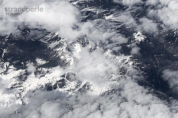 Blick aus dem Flugzeug auf eine schneebedeckte Landschaft mit Bergen und Wolken  Vogelperspektive  Island  Europa