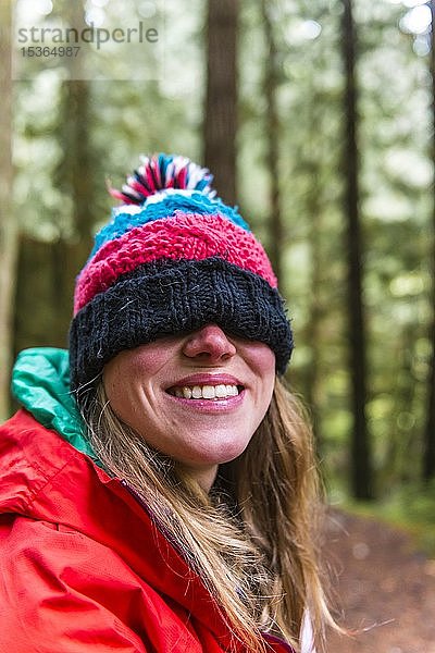 Porträt  lachende Frau mit Pudelmütze über den Augen im Wald  Mount Baker-Snoqualmie National Forest  Washington  USA  Nordamerika