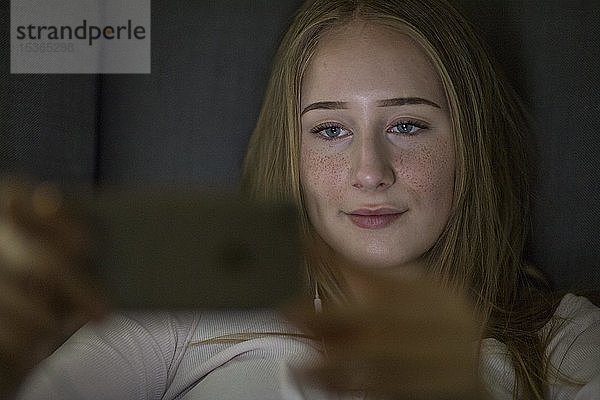 Teenager  Mädchen  geschminkt mit blauen Augen  spielt mit Handy  Deutschland  Europa