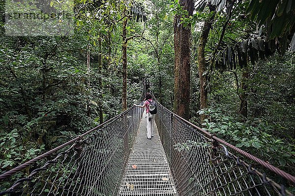 Wanderin auf einer Hängebrücke im tropischen Regenwald  Mistico Arenal Hängebrückenpark  Mistico Arenal Hängebrückenpark  Provinz Alajuela  Costa Rica  Mittelamerika