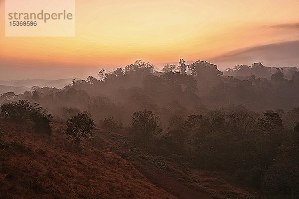 Sonnenaufgang mit morgendlichem Dunst über bewaldeten Hügeln  Provinz Mondulkiri  Kambodscha  Asien