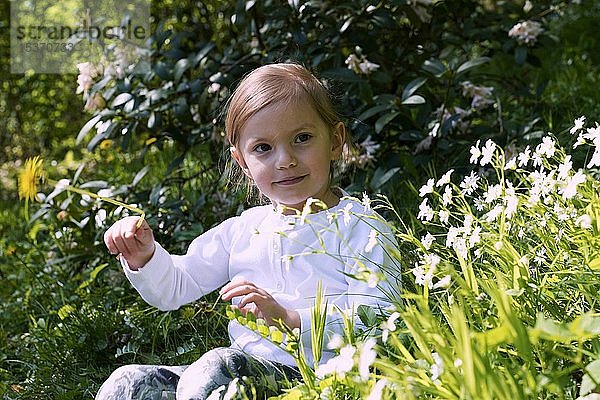 Kleines Mädchen sitzt zwischen Blumen auf der Wiese  Tschechische Republik  Europa