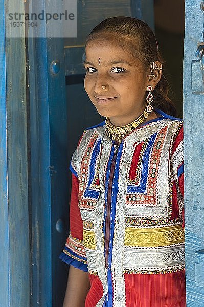 Junges Mädchen in traditioneller farbenfroher Kleidung steht in einer Tür  Khavda  Bezirk Kutch  Great Rann of Kutch  Gujarat  Indien  Asien