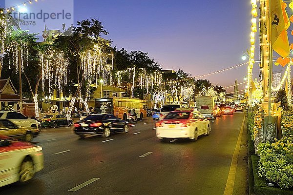 Beleuchtete  mit Lichtern geschmückte Straße mit Autoverkehr in der Abenddämmerung  Rachadamnoen Klang Road  Bangkok  Thailand  Asien