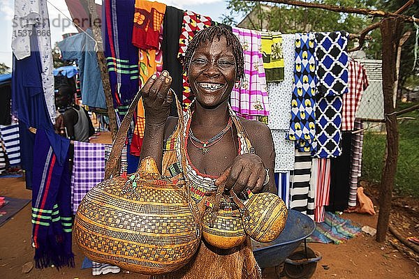 Lachende Frau der ethnischen Gruppe der Hamer verkauft kunstvoll verzierte Calabashe-Kürbisse  Markt in Dimeka  Unteres Omo-Tal  Region Omo  Südäthiopien  Äthiopien  Afrika