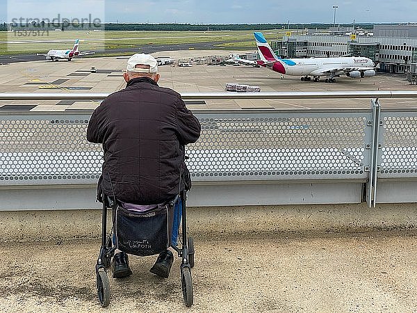 Behinderter Rollstuhlfahrer sitzt auf dem Flughafen mit Blick auf das Rollfeld  Düsseldorf  Deutschland  Europa