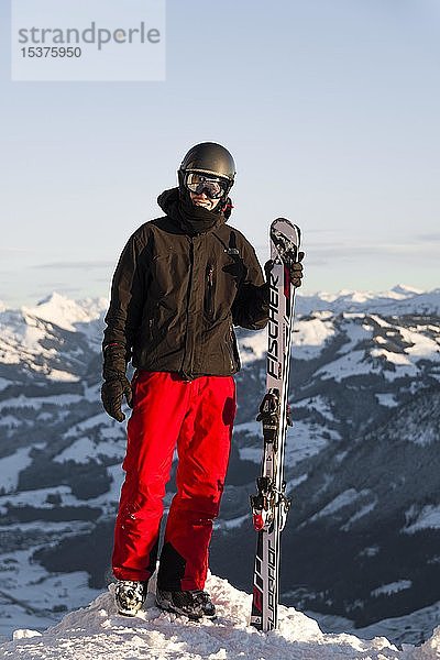 Skifahrer steht an der Piste und hält Ski  Blick in die Kamera  Gipfel Hohe Salve  SkiWelt Wilder Kaiser Brixenthal  Hochbrixen  Tirol  Österreich  Europa