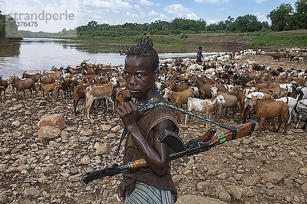 Ziegenhirte des Hamer-Stammes mit Kalaschnikow  bewacht Ziegenherde am Omo-Fluss  Murulle  Unteres Omo-Tal  Omo-Region  Südäthiopien  Äthiopien  Afrika