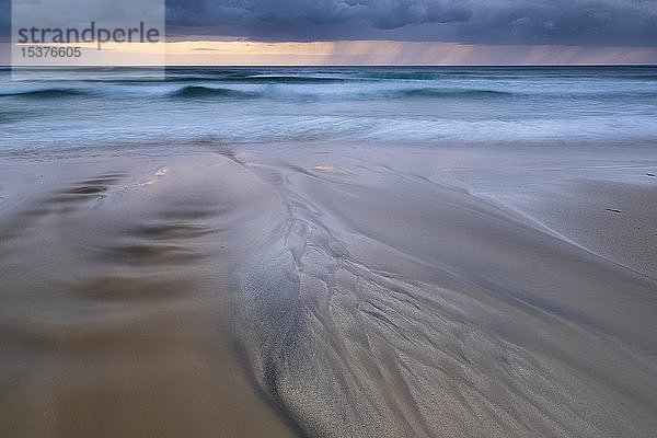 Wasser fließt über bizarre Strukturen am Sandstrand  Regenwolken über dem Meer  Dalmore Beach  Isle of Lewis  Schottland