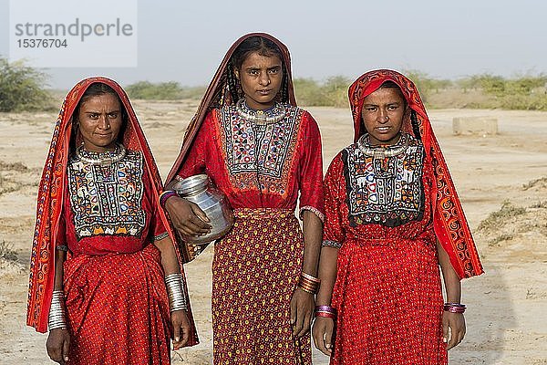 Drei Fakirani-Frauen in traditioneller bunter Kleidung mit einem Wasserkrug  Great Rann of Kutch  Gujarat  Indien  Asien