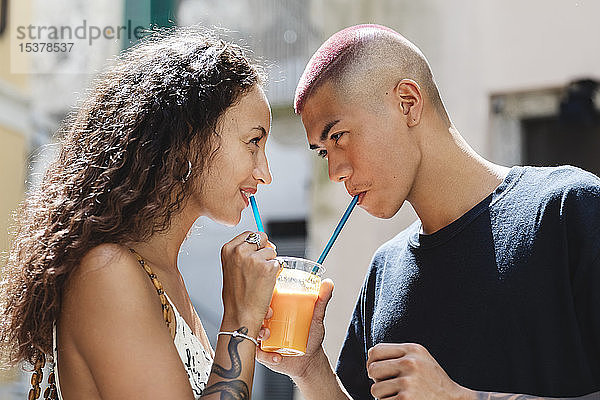 Junges Paar trinkt gemeinsam Fruchtsaft