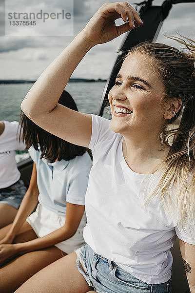 Glückliche junge Frau mit Freunden bei einer Bootsfahrt auf einem See