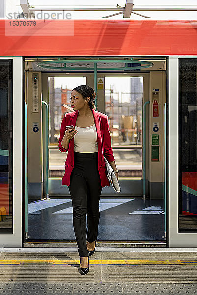 Geschäftsfrau mit Mobiltelefon beim Aussteigen aus dem Zug  London  UK