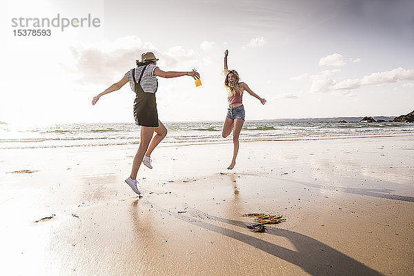 Zwei Freundinnen amüsieren sich  rennen und springen am Strand