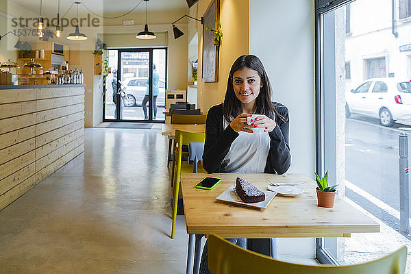 Porträt einer lächelnden jungen Frau  die in einem Cafe sitzt