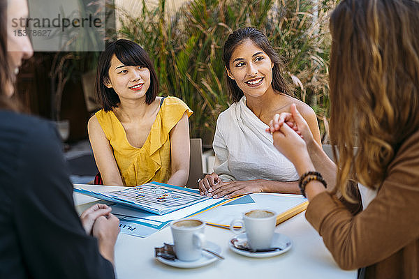 Weibliche multikulturelle Studentinnen treffen sich in einem Café und organisieren ihren Stundenplan