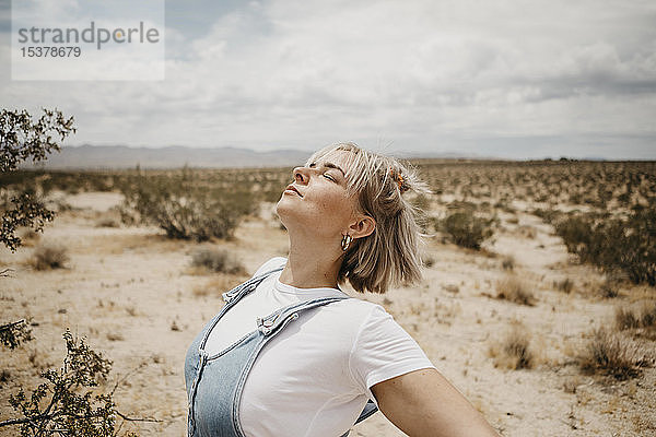 Junge Frau in Wüstenlandschaft mit geschlossenen Augen  Joshua-Tree-Nationalpark  Kalifornien  USA