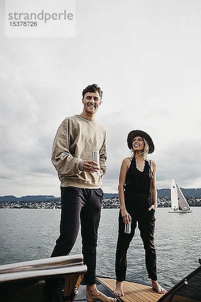 Glückliches junges Paar bei einem Drink während einer Bootsfahrt auf einem See