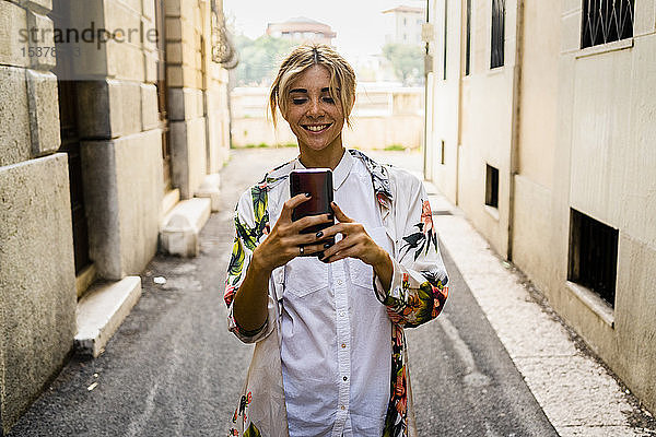 Lächelnde Frau mit Smartphone in der Stadt