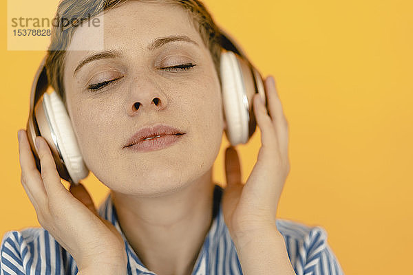 Porträt einer musikhörenden Frau mit orangem Hintergrund