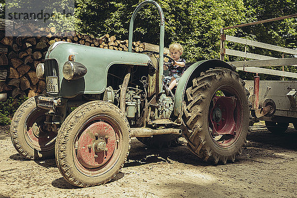 Kleiner Junge  der vorgibt  einen Traktor zu fahren