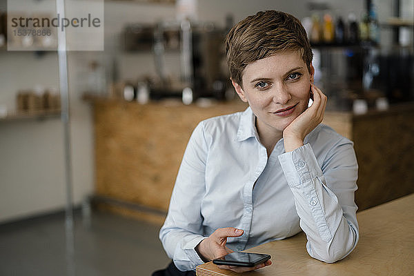 Porträt einer selbstbewussten Frau mit Handy in einem Cafe