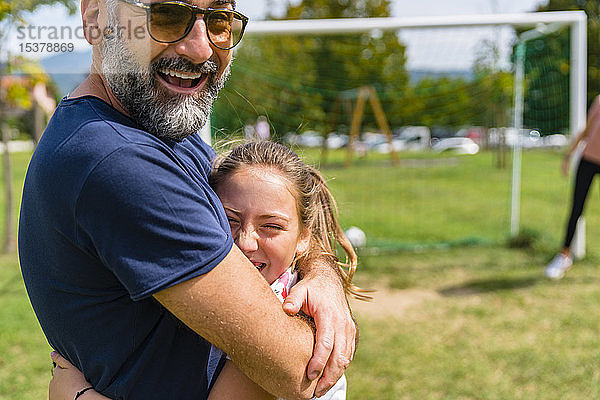 Glückliche Vater und Tochter umarmen sich auf einem Fussballplatz