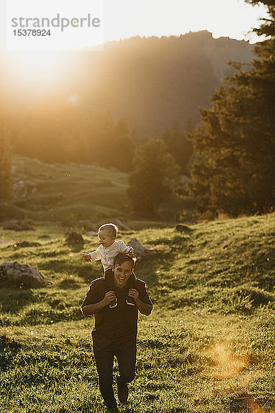 Glücklicher Vater trägt den kleinen Sohn auf den Schultern auf einer Wanderung bei Sonnenuntergang  Schwaegalp  Nesslau  Schweiz
