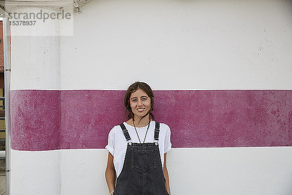 Porträt einer lächelnden jungen Frau vor der Wand