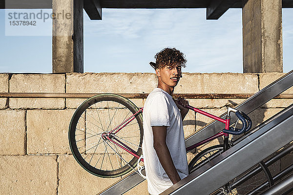 Junger Mann auf der Treppe  Fahrrad auf den Schultern tragen