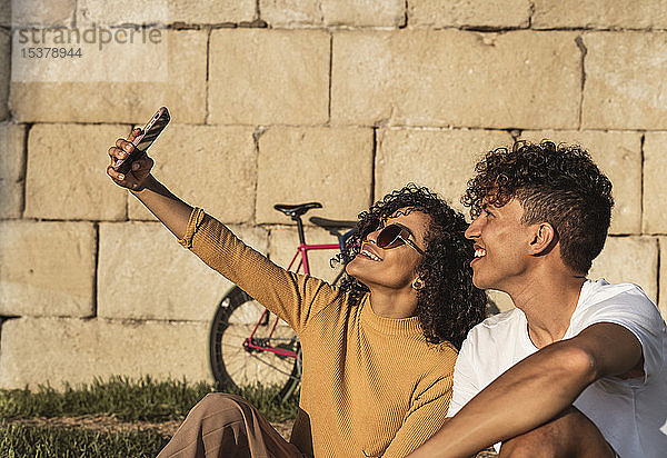 Junges Paar  das sich mit einem Smartphone selbstständig macht und vor der Wand sitzt