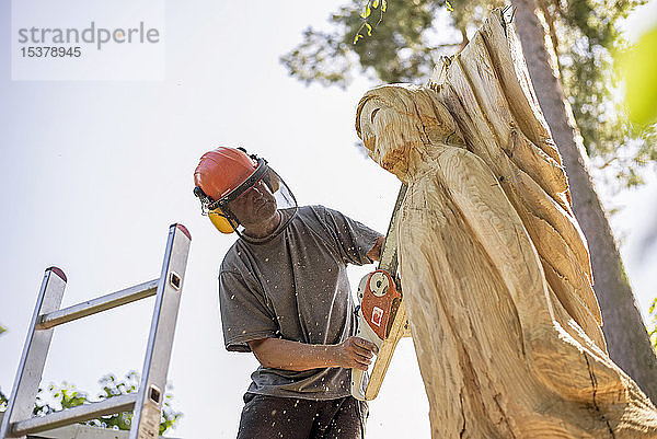 Holzschnitzerin schnitzt Engel-Skulptur  mit Kettensäge