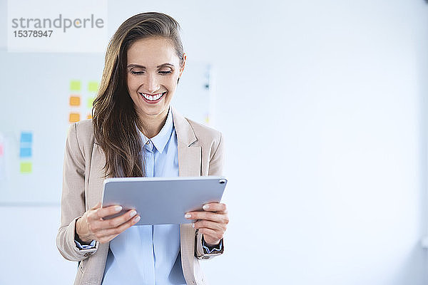 Lächelnde Geschäftsfrau benutzt Tablett im Büro