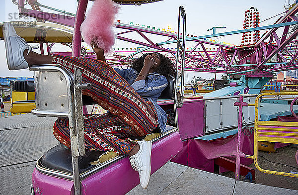 Lachende junge Frau mit rosa Zuckerwatte auf dem Jahrmarkt