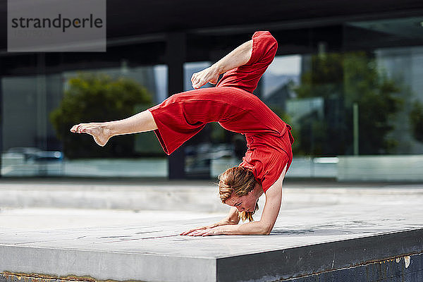 Sportliche junge Frau macht Akrobatik im Freien