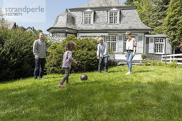 Glückliche Grossfamilie spielt Fussball im Garten