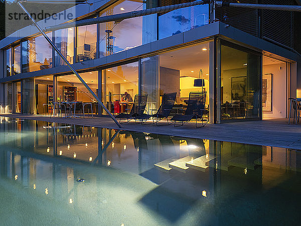 Schweiz  beleuchtete moderne Villa in der Dämmerung mit Pool im Vordergrund