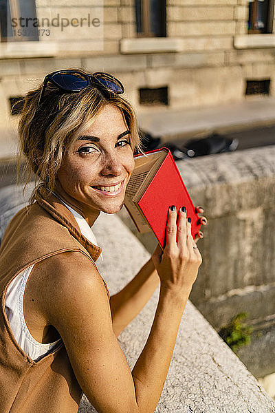 Porträt einer lächelnden Frau mit Buch im Freien