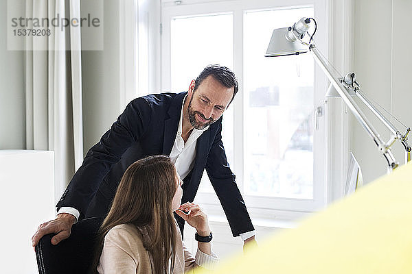 Geschäftsmann und Angestellter sprechen am Schreibtisch im Büro